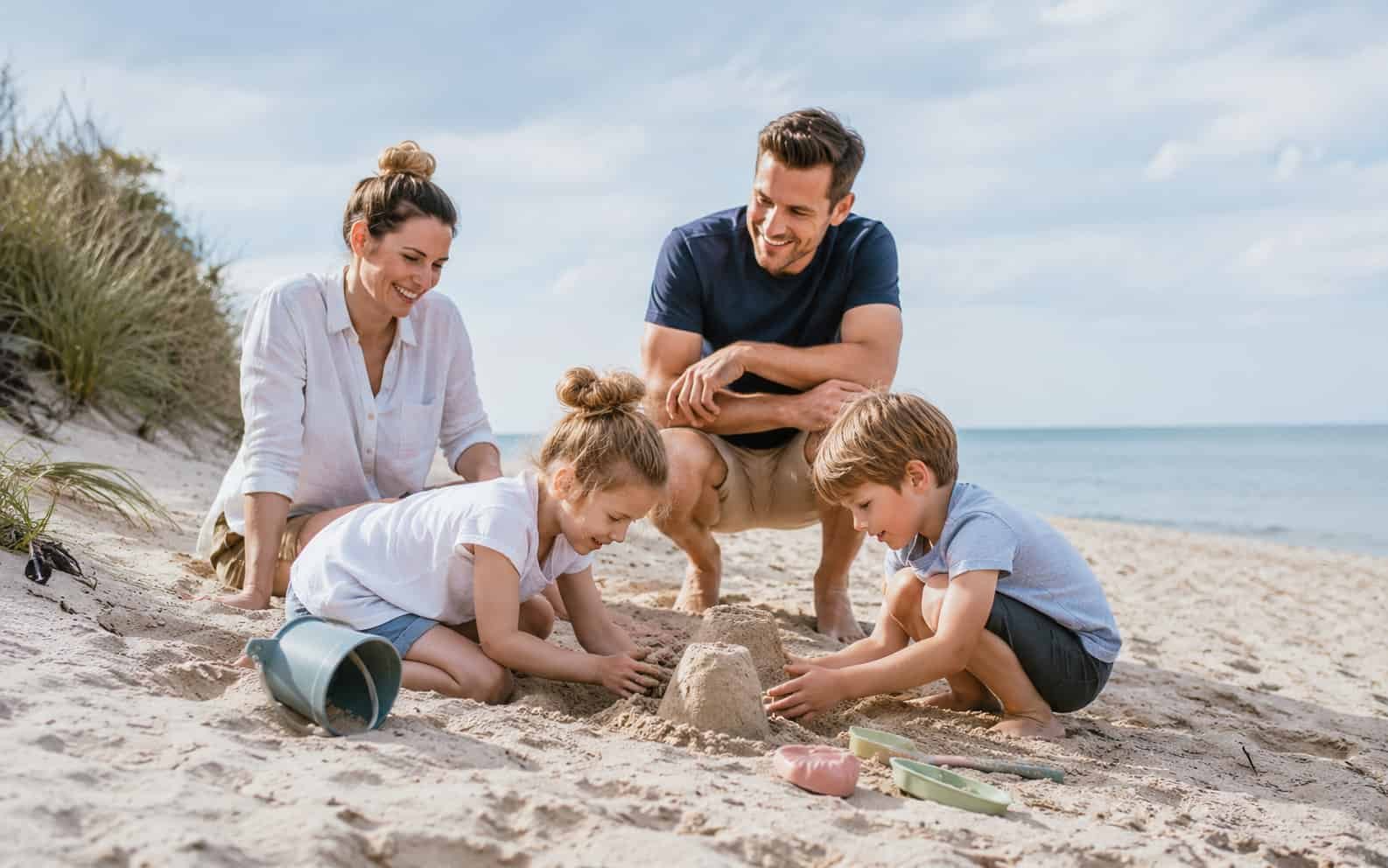 Kinder spielen mit ihren Eltern an einem ruhigen Ostseestrand