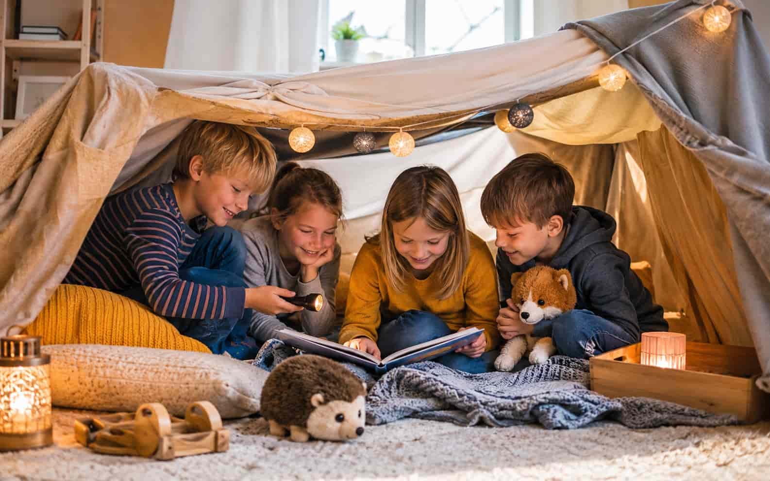 Kinder sitzen fröhlich in einer selbstgebauten Deckenhöhle zuhause